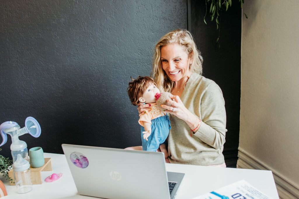 Loveland IBCLC nursing support- woman holding baby doll, showing how to breastfeed via video chat.