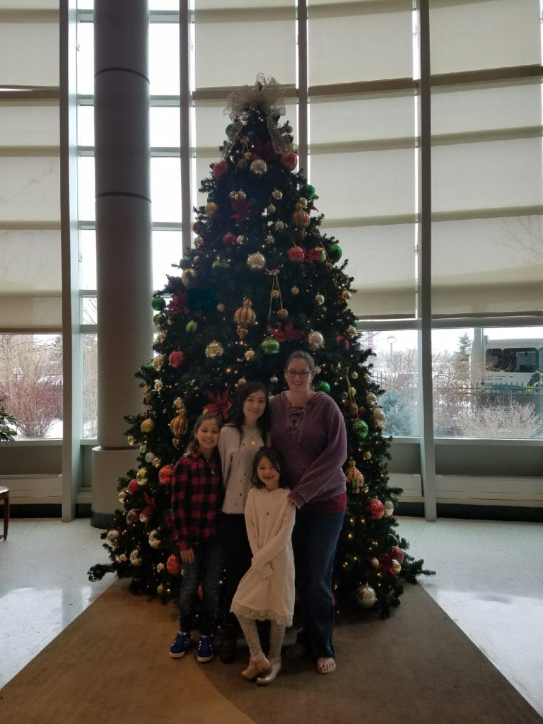 The pregnant author with her three daughters in front of a Christmas tree in the lobby of University of Colorado Anschutz in Aurora Colorado