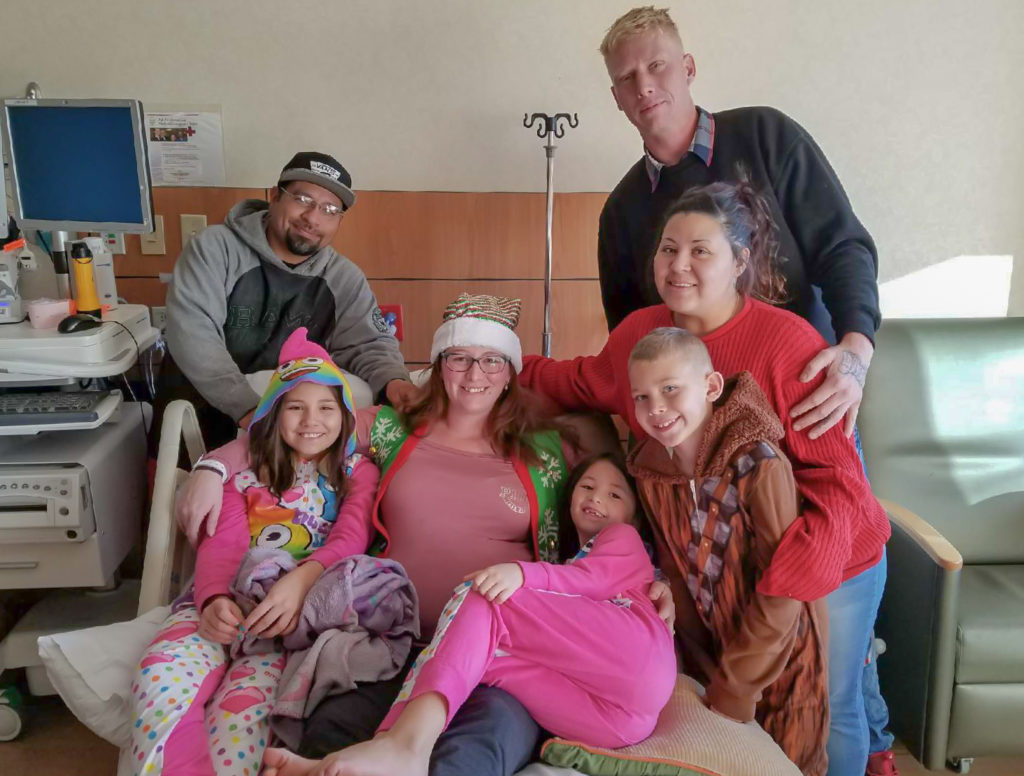 Family surrounding the pregnant author in a hospital bed during Christmas holiday. 