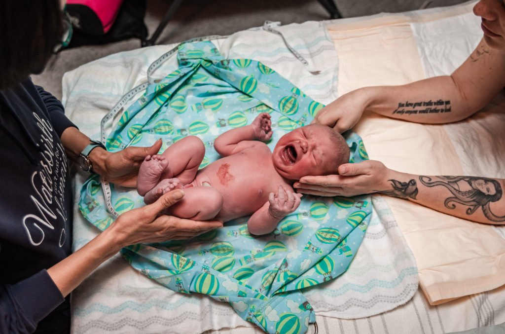 Tattooed mom and home birth midwife examining baby after a home birth in Frederick Colorado