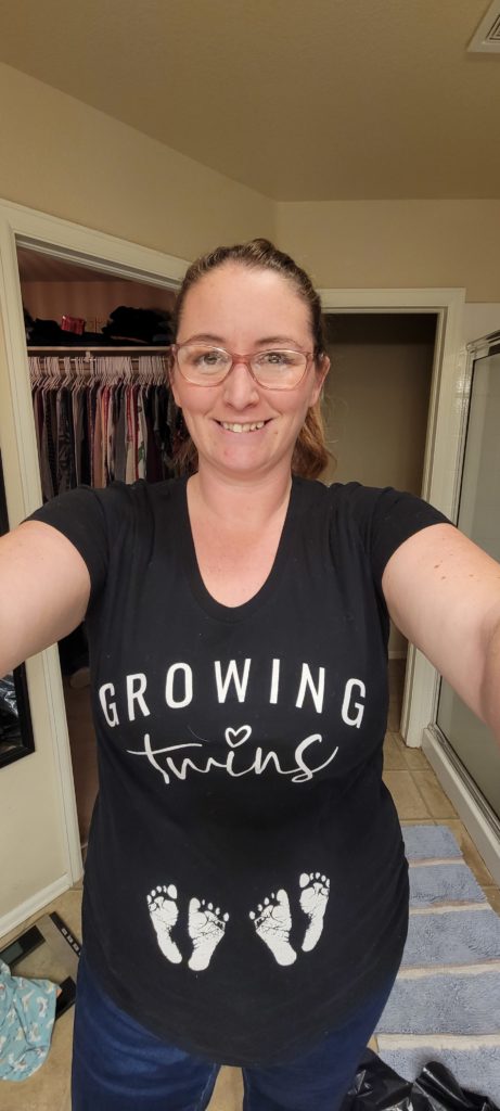 Photo of mom wearing shirt that says "growing twins" with two sets of baby feet underneath. Pregnancy announcement