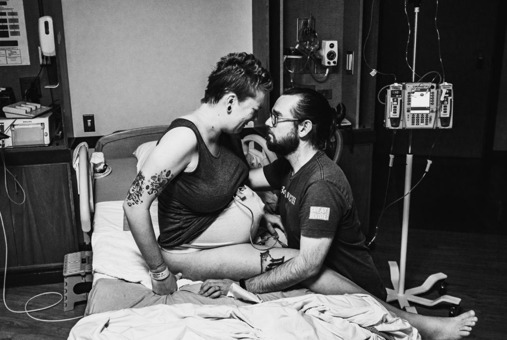 Birth partner supporting mom during labor contractions in hospital bed at Avista hospital in Colorado