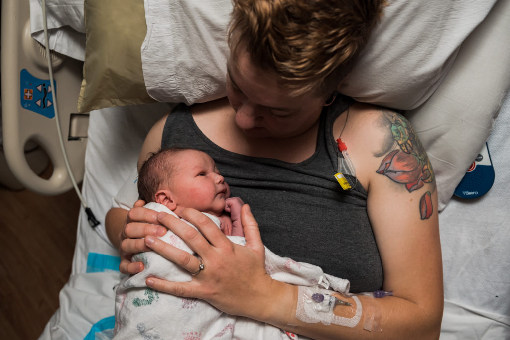 Tattooed mom holding baby in hospital bed after cesarean birth at Avista hospital in Colorado 