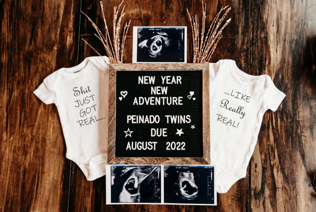 New Years pregnancy announcement. Letterboard reads "New Year New Adventure Peinado Twins Due August 2022" There is a baby shirt on either side of the letterboard that read "shit just got real..." and "...like really real!" There are 3 twin ultrasound photos around the letterboard.