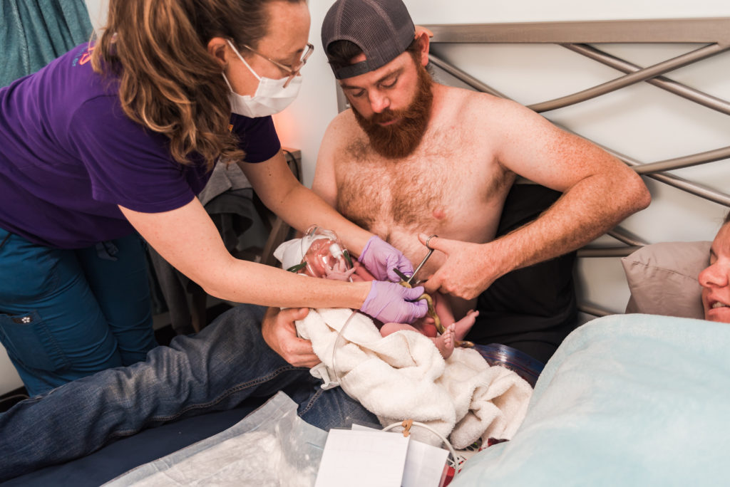 Midwife helps dad cut the umbilical cord
