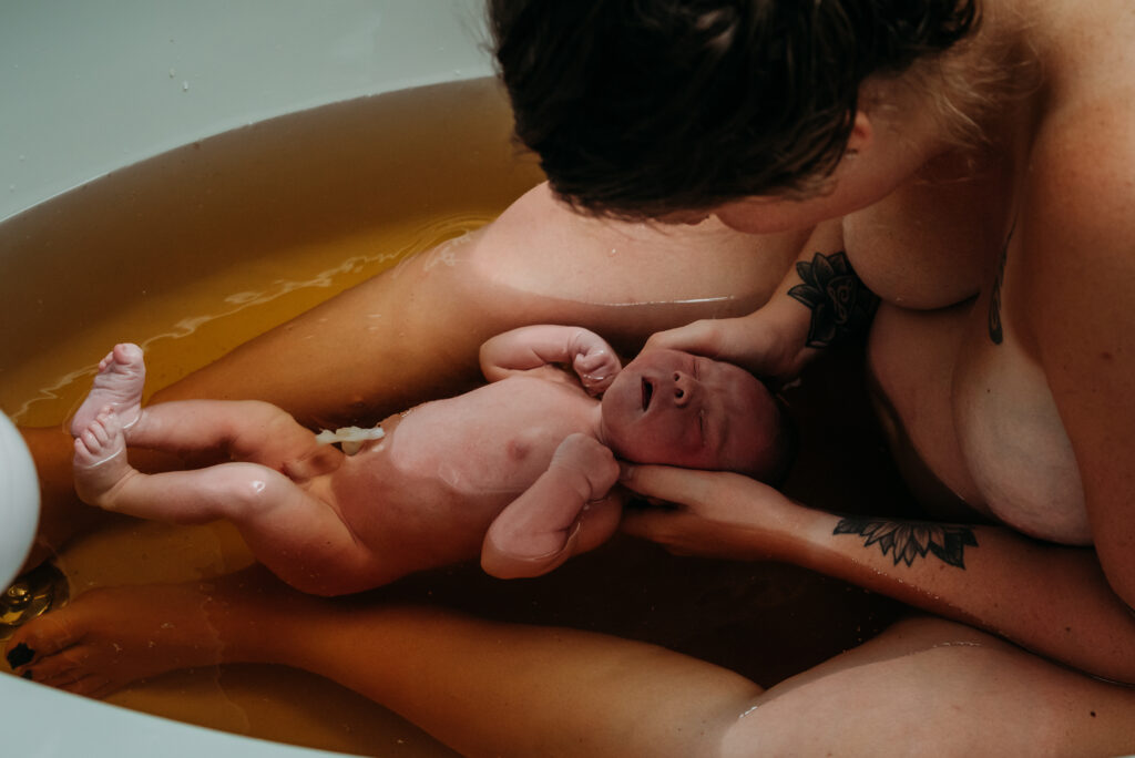 Mom and just born baby in an  herbal bath after her Johnstown Colorado home birth.