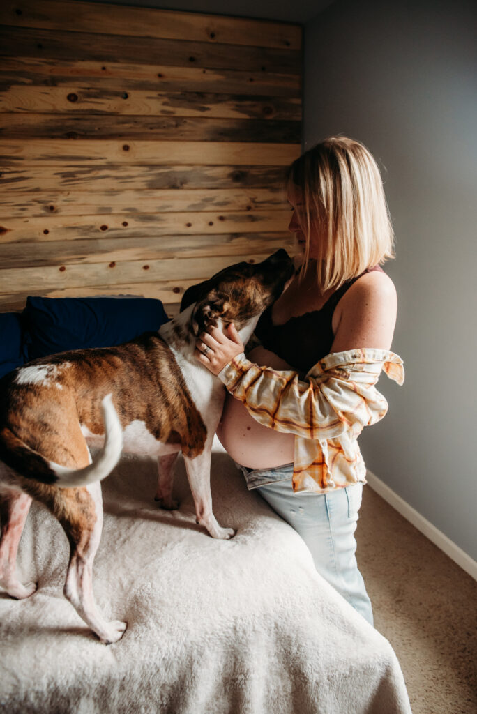 pregnant mom loving on her dog during her in home maternity photoshoot in Colorado