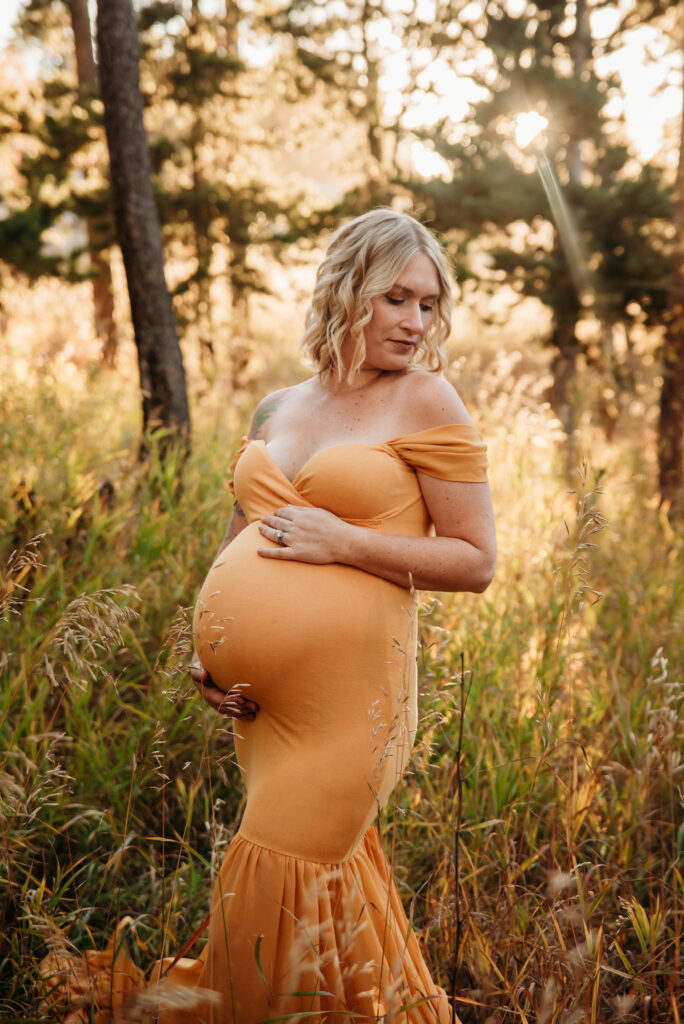 mom wearing yellow maternity dress in golden lighting in Nederland Colorado