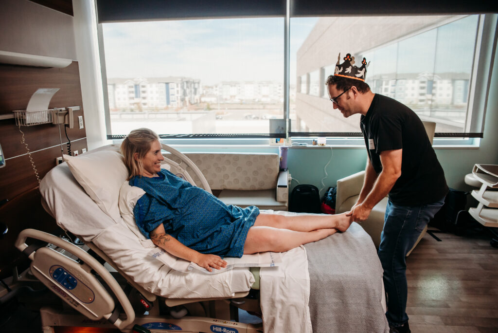 Dad being silly wearing a paper crown while rubbing laboring mom's feet in Longmont Colorado