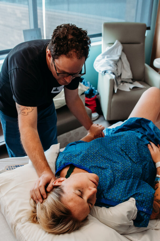 Dad caressing laboring moms head and hair in support while mom squeezes dad's hand through a contraction. 