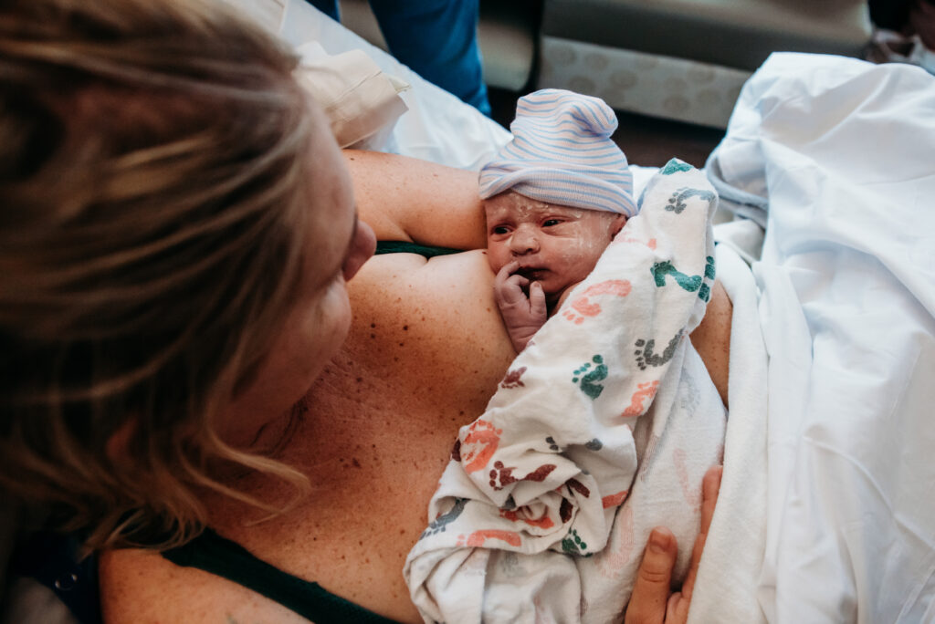 mom holding brand new baby covered in vernix after giving birth at Longs Peak hospital in Colorado