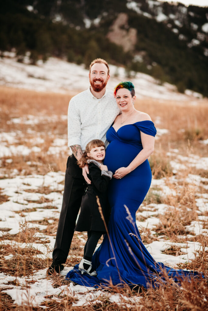 Family maternity photo with mom dad and daughter in front of the Boulder CO flatirons.