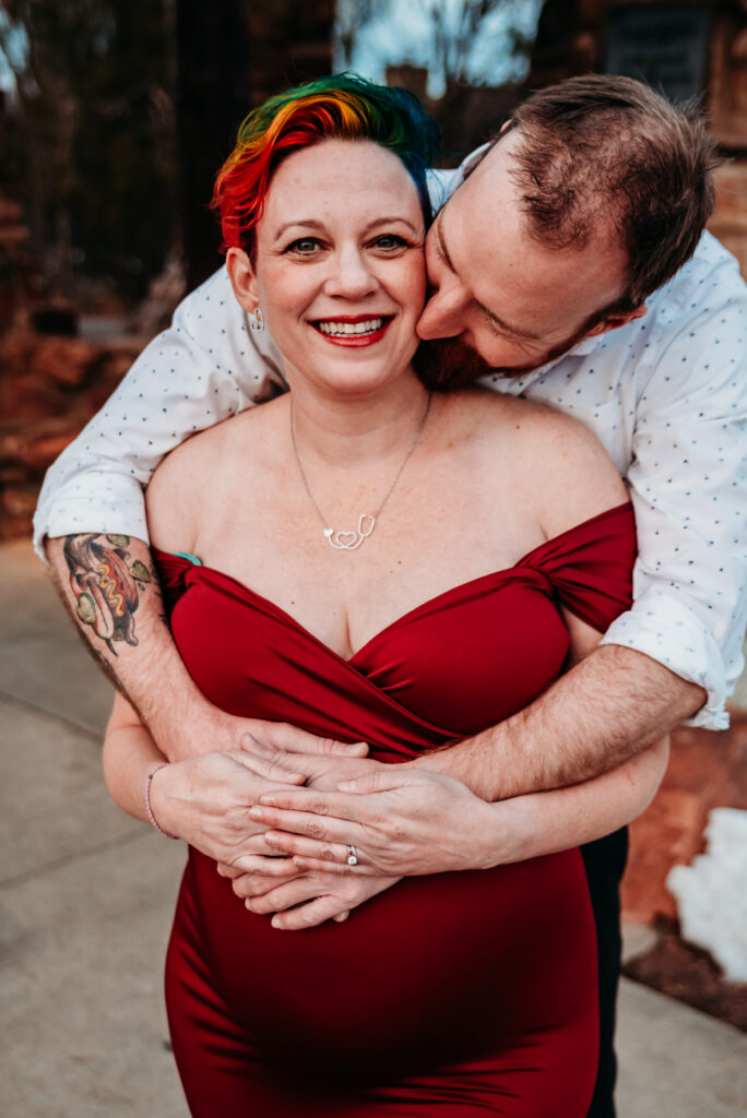 Husband kissing pregnant wife'cheek during maternity photo session in Boulder CO