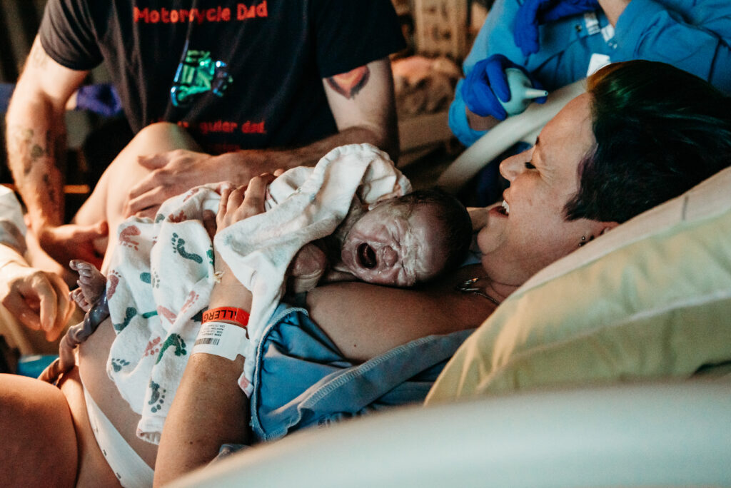 Mom smiling holding her baby for the first time, part of her birth story.