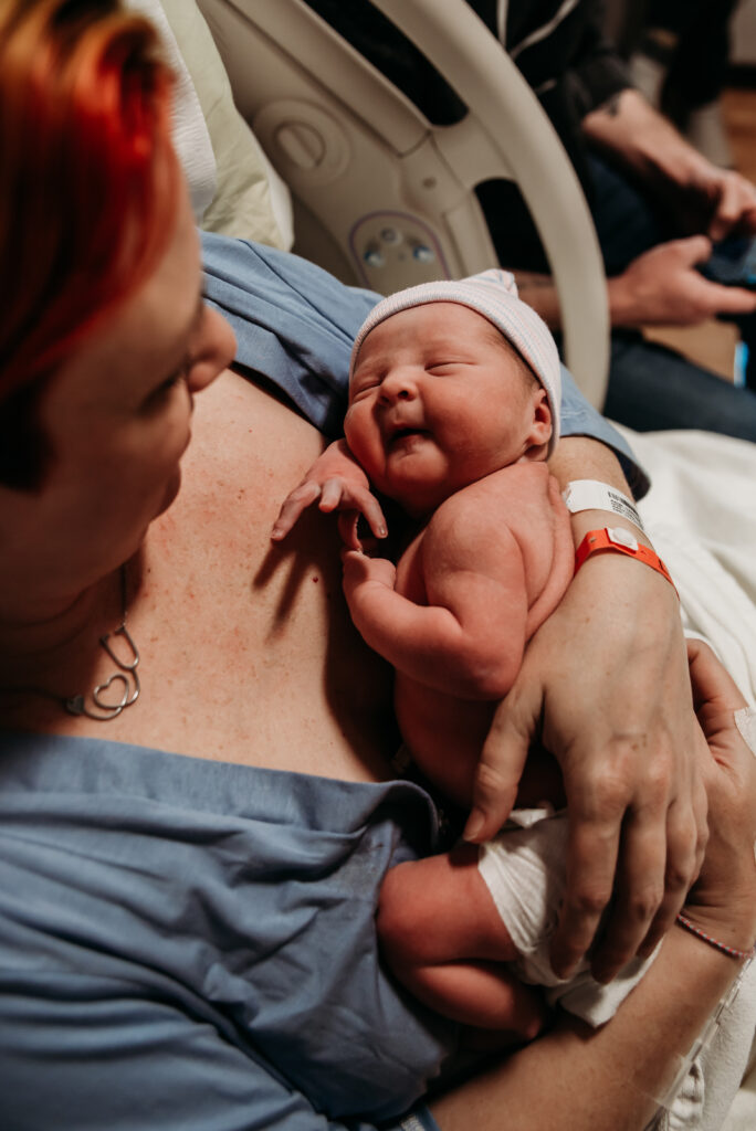 Mom holding chunky baby boy in a hospital bed in Longmont CO after he was just born.