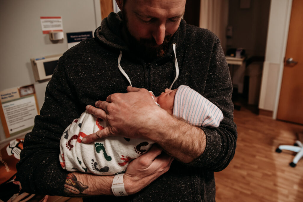 Dad holding baby swaddled in the feet print baby blanket at Longmont United Hospital