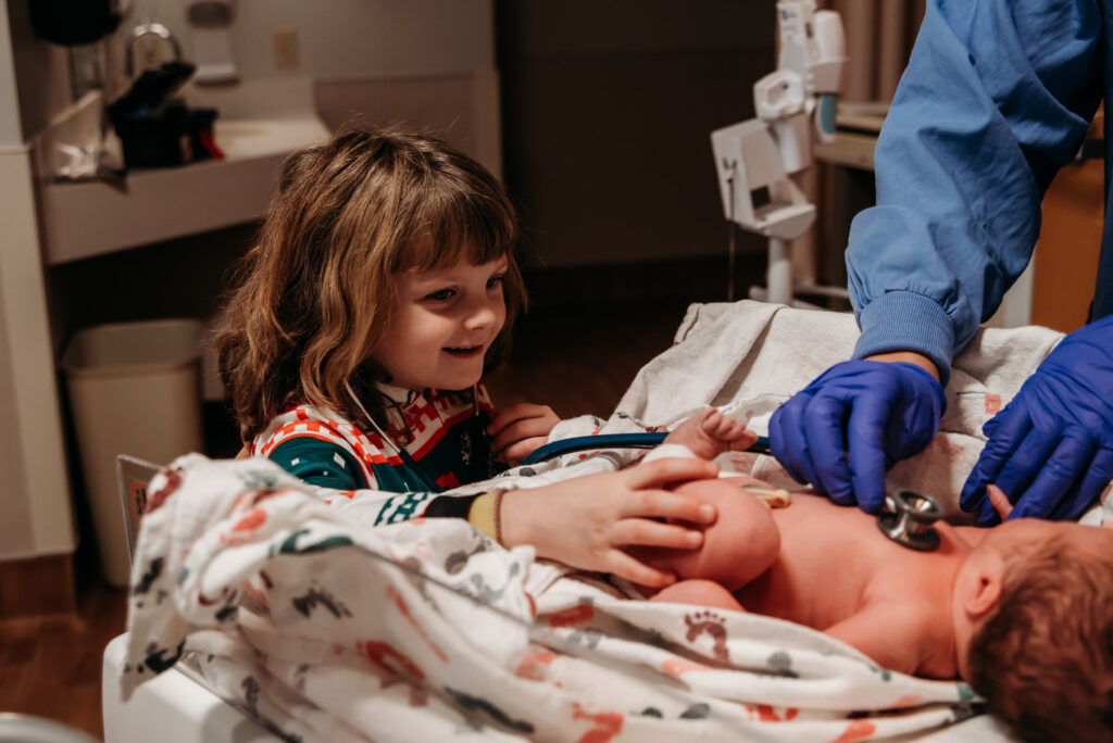 Big sister meeting and touching her baby brother for the first time in Longmont Colorado