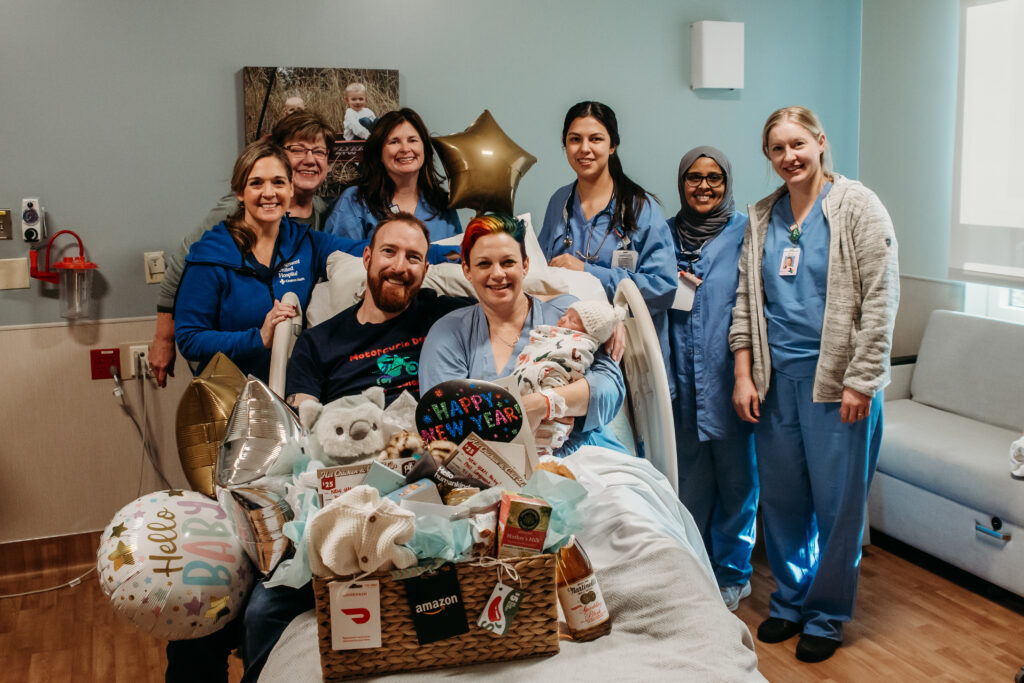 The first birth at Longmont United Hospital in 2024. Photo of the staff on duty and the family with their new baby, and the gift basket from the staff.