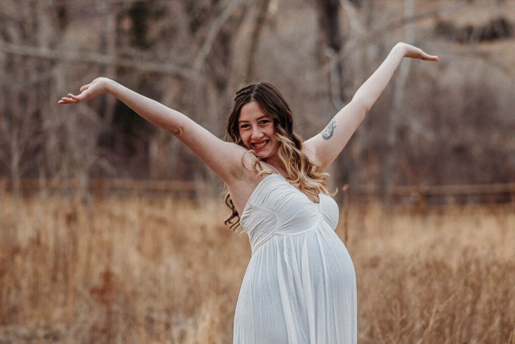 Mom throwing her hands up in the air with joy during her maternity photo shoot in Boulder Colorado