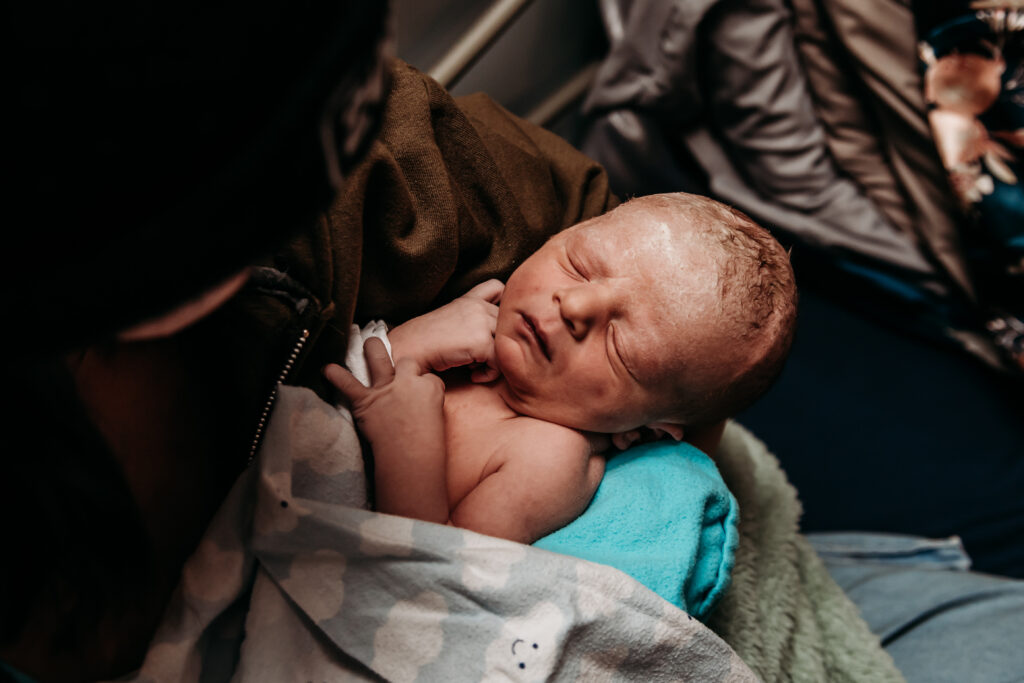 Just born baby boy held on the bed at Seasons community birth center