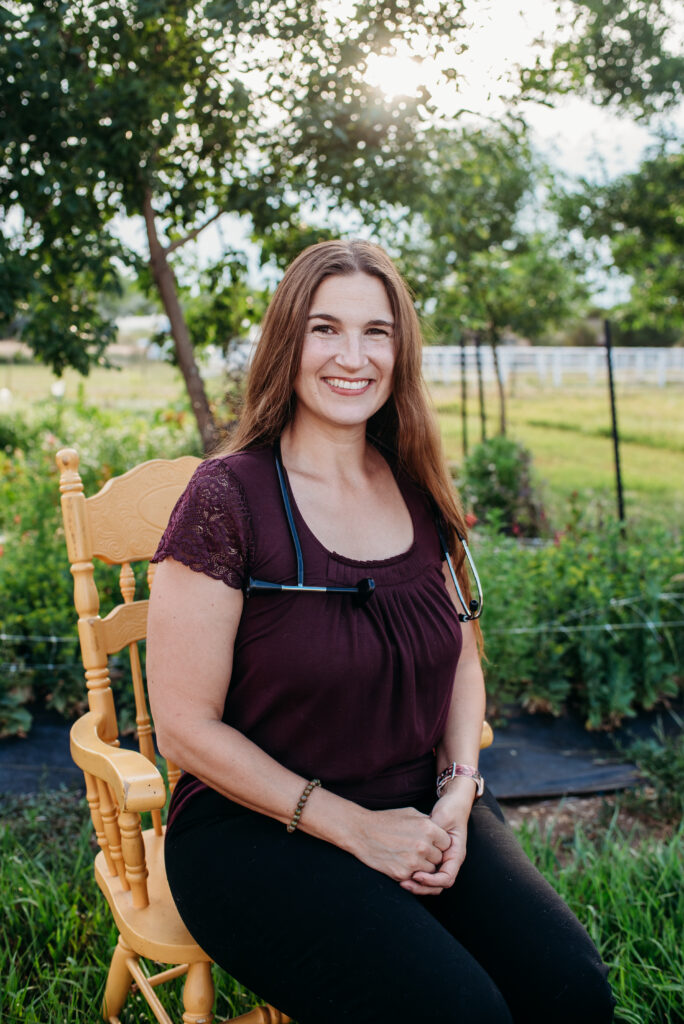 Northern CO home birth midwife sitting on a chair in a garden with a doppler around her neck