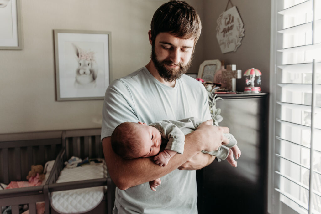 dad holding new baby in nursery