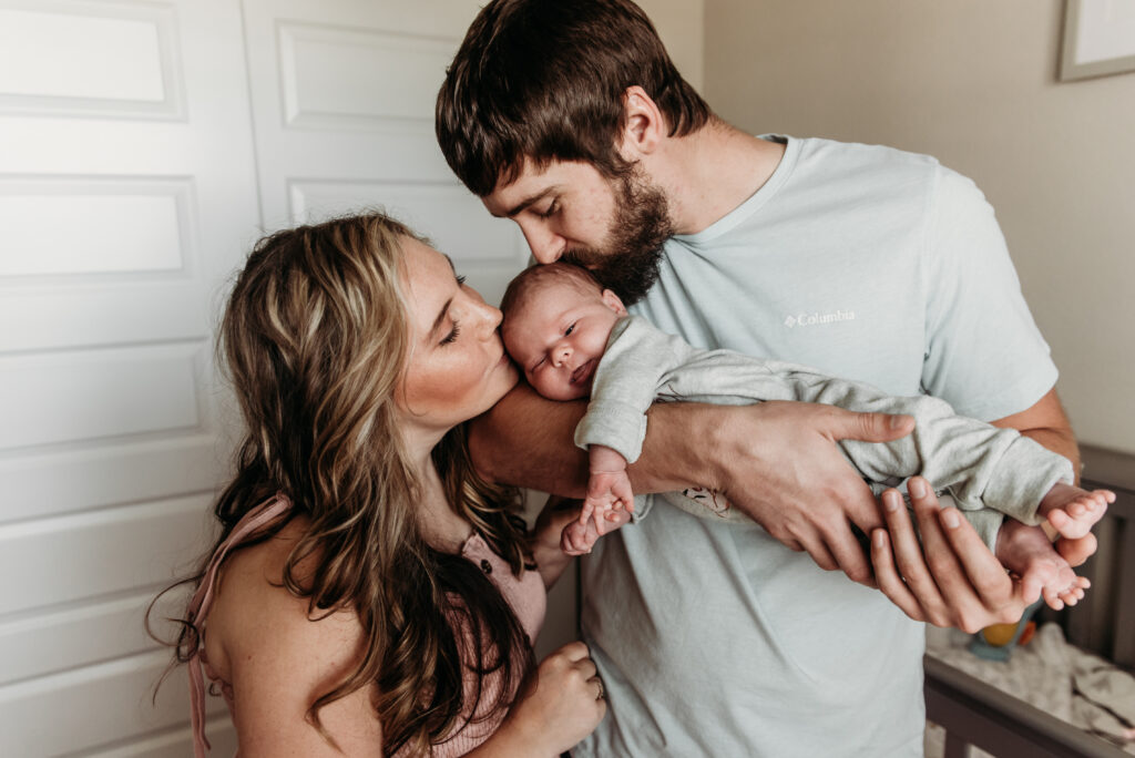 mom and dad kissing baby in home photo session