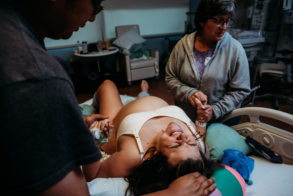 Laboring mom in hospital bed at Children's Hospital Colorado. Documentary birth photography.