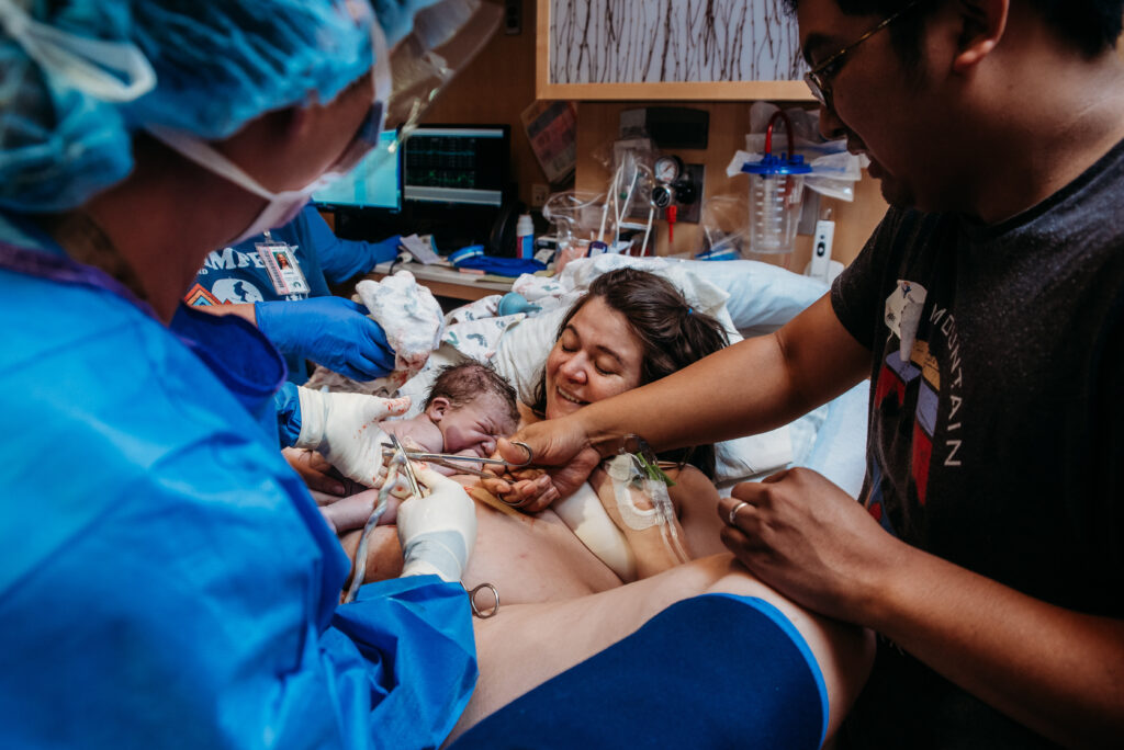 Birth photograph of dad cutting baby's cord