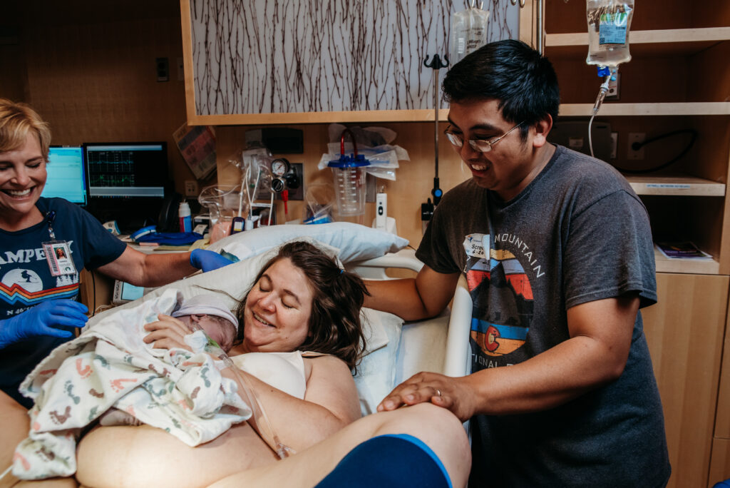 mom and dad smiling at new baby right after birth.