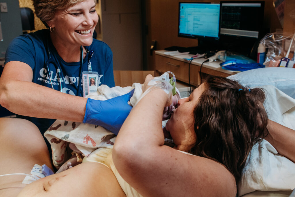 Mom kissing baby as nurse takes him to the baby warmer. Birth documentary photography.