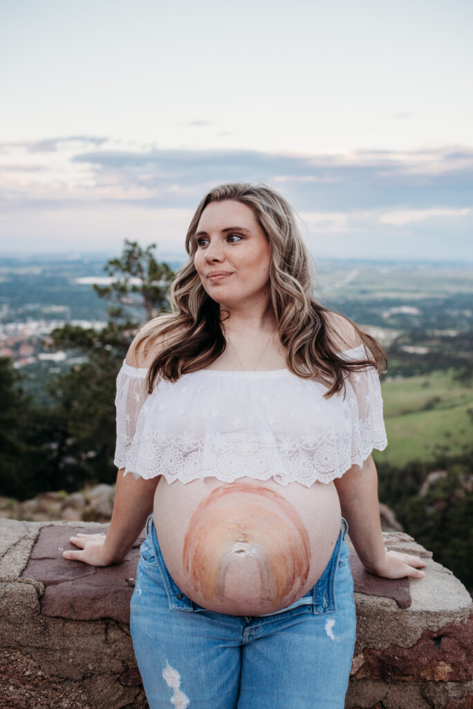 Rainbow painted on bare pregnant belly. Boulder mountain photography.