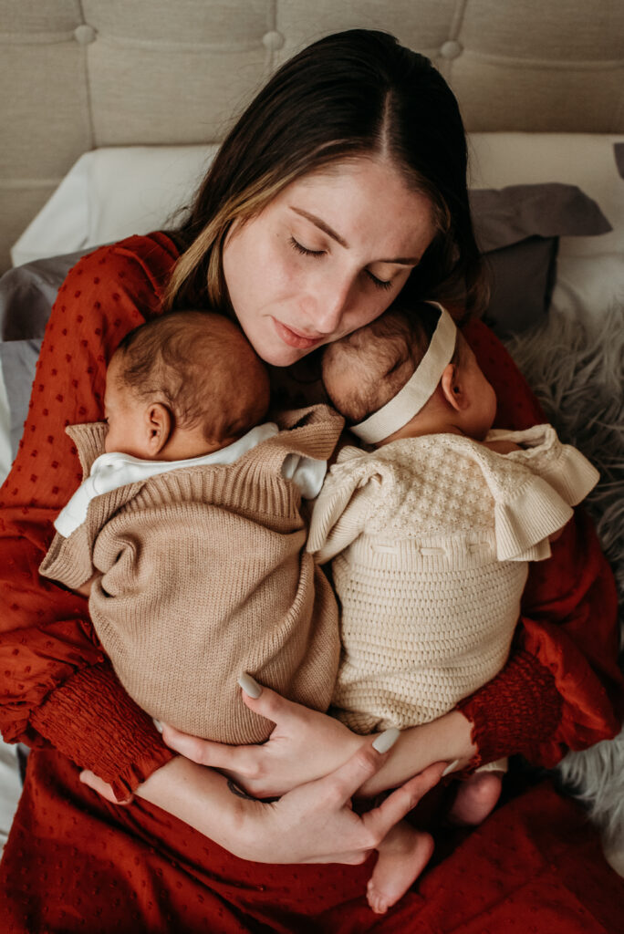 mom holding her twins in her bed for her in home photo session