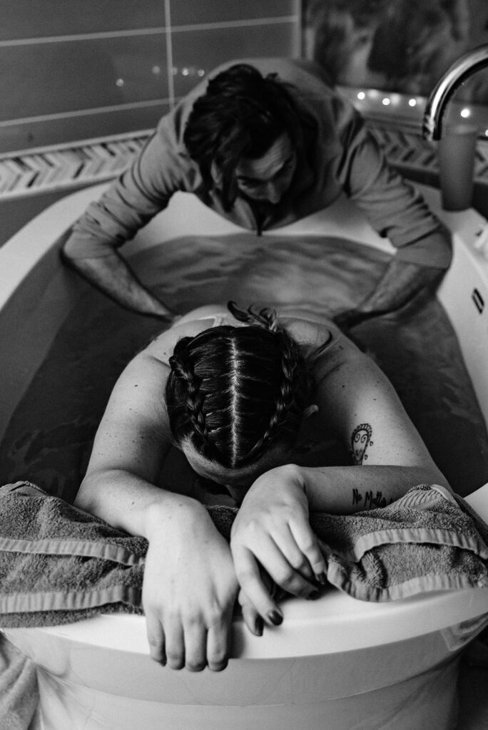 Photo of dad giving laboring wife hip squeezes while she is in the birth tub at Season's Birth Center