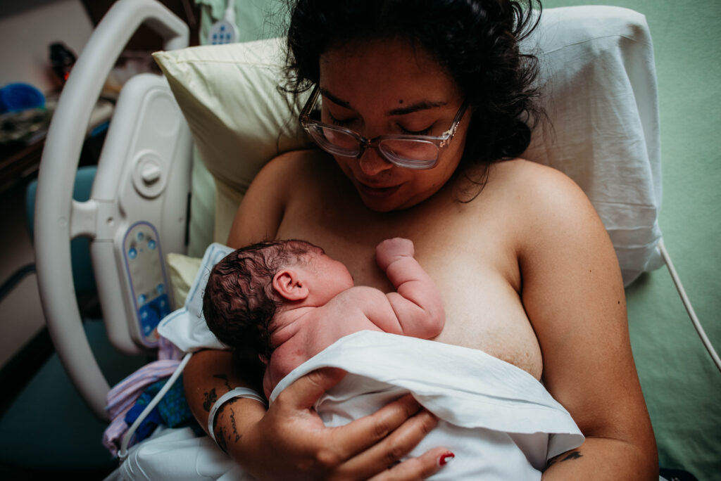 Baby with rolls being held by mom in hospital bed in Longmont CO