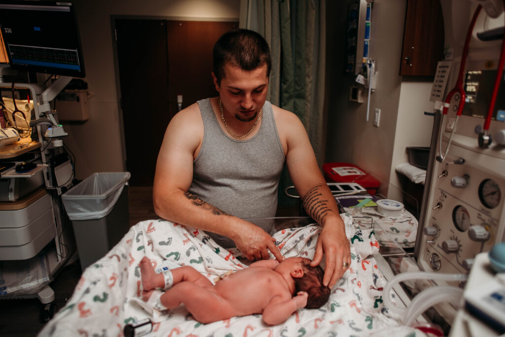 Dad holding new daughter's hand in the hospital after being born at Longs Peak Hospital Colorado